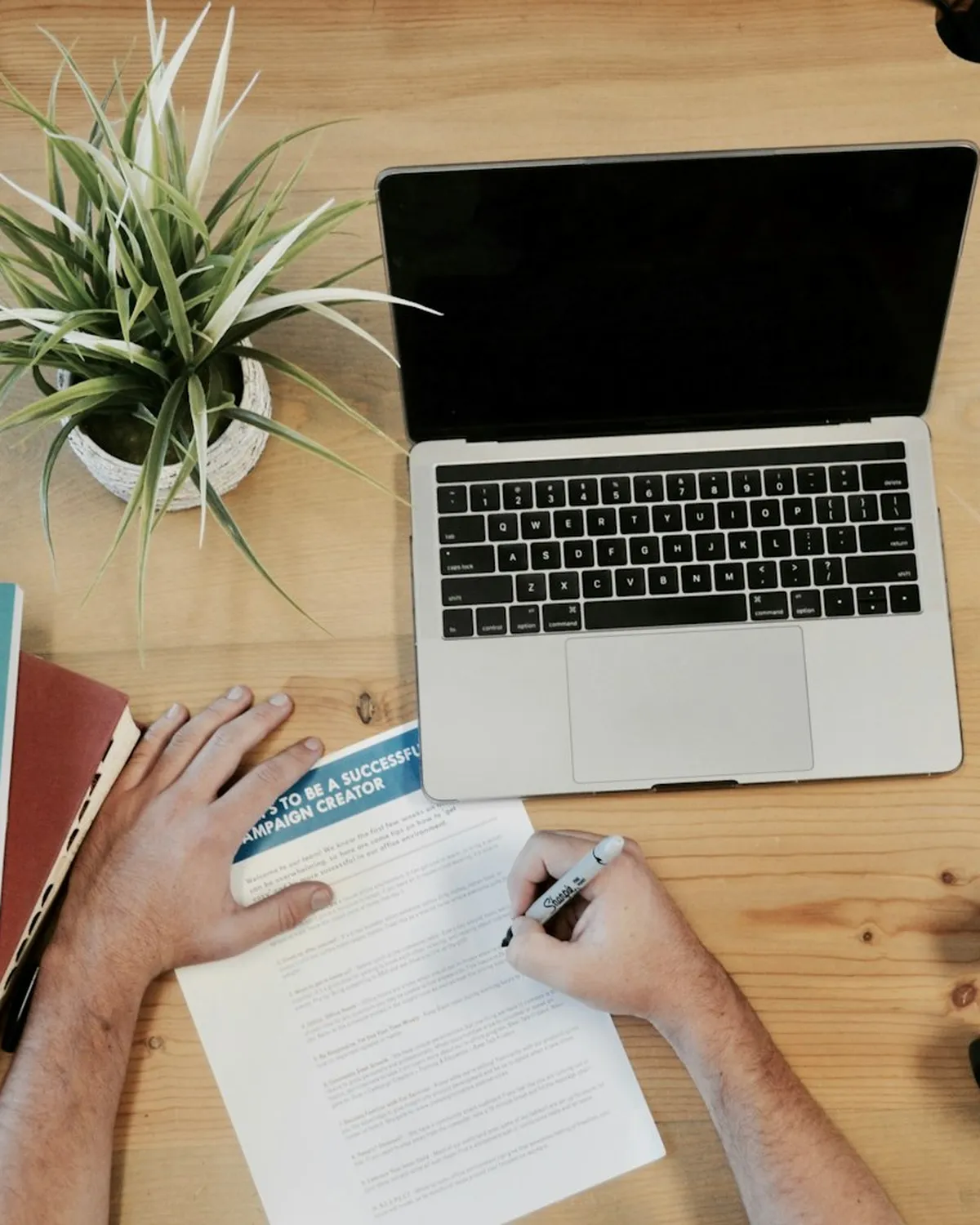 Mesa de trabalho de marketing com notebook, anotações e o livro Marketing and Pricing